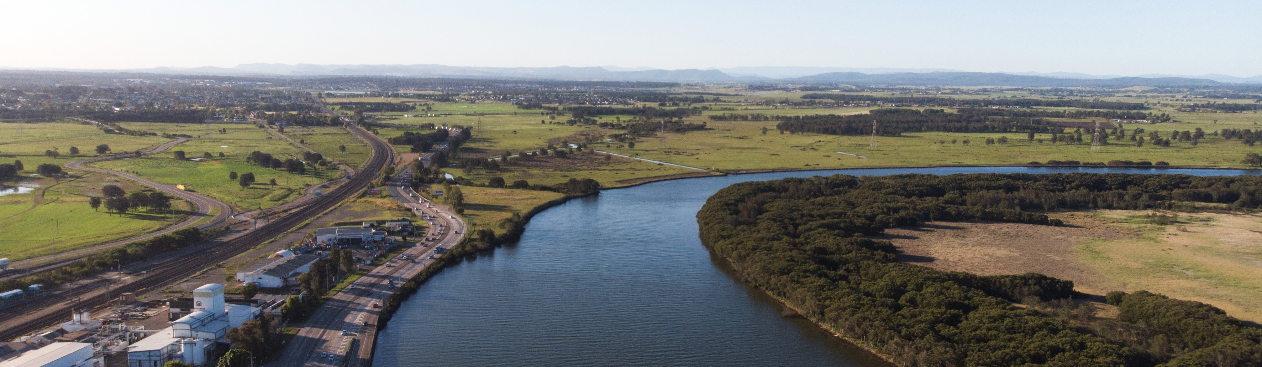 Scenic view across river showing industry, agriculture and infrastructure